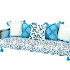 a couch with blue and white pillows sitting on it's back end, in front of a white background