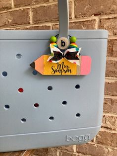 a back to school bag hanging on the side of a brick wall with a name tag attached