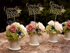 four small vases with flowers in them sitting on a wooden table next to each other