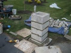 a man sitting on the ground next to a pile of cement blocks and other items