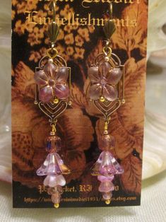 Edwardian elegance is revisited in this  pair of Art Nouveau earrings. Reproduction brass stampings form the base of the earring.  A Czech glass flower bead is dropped from the ear wire, followed by more Czech glass baby bell beads and filagree bead caps. Your choice of pink or green. FREE shipping in the continental USA!! FREE gift wrapping upon request. Vintage Gold Czech Glass Earrings, Czech Glass Dangle Earrings With Bead Caps, Gold Flower-shaped Czech Glass Earrings, Vintage Czech Glass Beaded Earrings As Gift, Gold Flower-shaped Earrings With Czech Glass, Gold Flower Earrings With Czech Glass, Bohemian Gold Earrings With Bead Caps, Vintage Czech Glass Earrings With Dangling Beads, Elegant Flower Earrings With Czech Glass