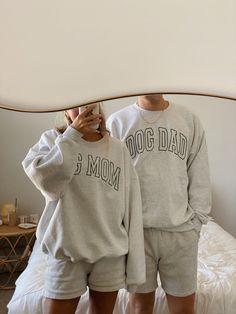 two people standing in front of a mirror wearing matching sweatshirts and shorts with the words dog dad on them