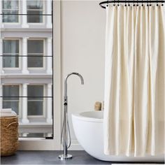 a white bath tub sitting next to a shower curtain in front of a tall building