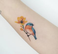 a small blue bird sitting on top of a flower next to a yellow flower tattoo