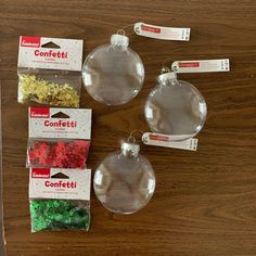 four clear christmas ornaments sitting on top of a wooden table