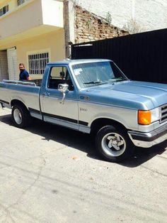 a blue and white truck parked in front of a building with a man standing next to it