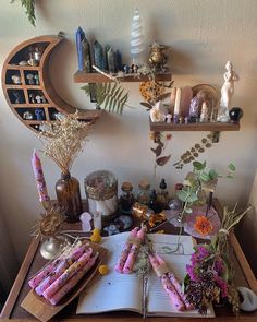 an open book sitting on top of a wooden table next to flowers and candles in vases