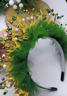 a green and yellow headband with beads on it's side, being held by a hand