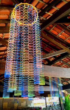 a multicolored sculpture hanging from the ceiling in a room with exposed wood beams