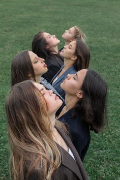 four women are laying on the grass and looking up at something in the air with their mouths open