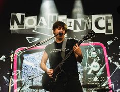 a man holding a guitar while standing in front of a microphone