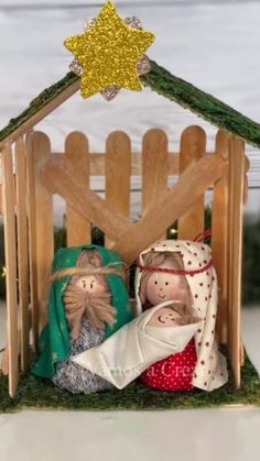 two nativity figurines in a wooden stable with a star on the roof