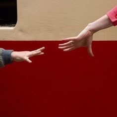 two people reaching out their hands to touch each other on a red and beige background