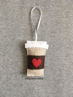 a coffee cup ornament with a heart on the front and bottom, hanging from a cord