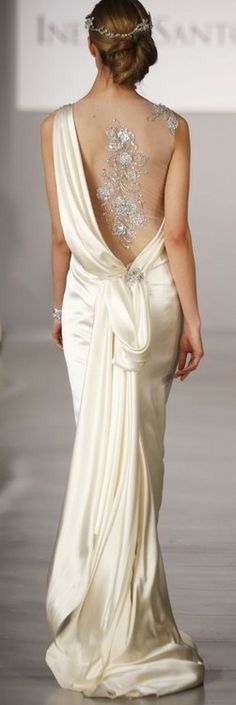 a woman walking down a runway wearing a dress with an open back and beading on it