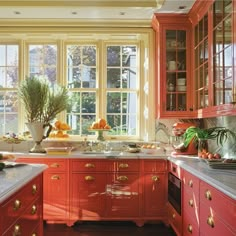 a kitchen filled with lots of red cabinets and counter top space next to a window