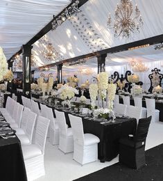 tables and chairs are set up in a tent for a formal function with chandeliers