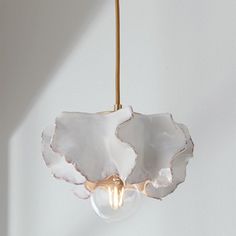 a light bulb hanging from a ceiling fixture with white and gold leaf designs on it