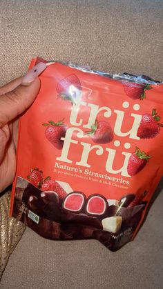 a hand holding a bag of fruit from nature's strawberry - filled chocolates