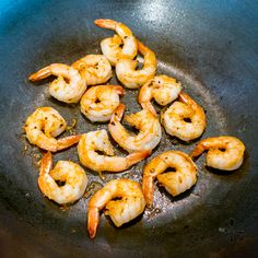 shrimp being cooked in a frying pan with oil on the bottom and no one around it