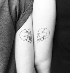 two people with tattoos on their arms holding each other's hands and one has a skull