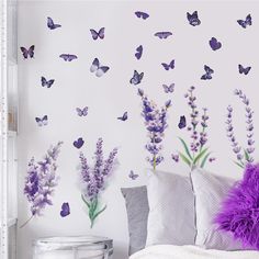 purple butterflies and lavender flowers on a white wall behind a bed in a room with grey pillows