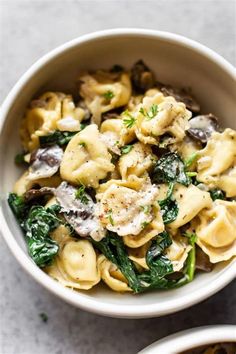 pasta with mushrooms and spinach in a white bowl