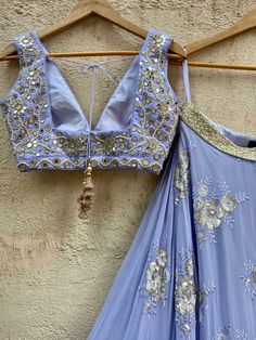 A three-piece periwinkle blue butti lehenga set from the Priti Sahni collection. This elegant blue georgette umbrella lehenga with big sequin and thread work butti and gota work border is paired with a blue raw silk blouse with mirror and thread work hand embroidery. The lehenga has side hanging ball tassels to the waistline. And the blouse has a sequins tassel tie-up at the back. The outfit is completed with a periwinkle blue tulle ruffle dupatta with pearl work edging. Embellished Blue Anarkali Pre-draped Saree, Blue Embellished Georgette Sets, Blue Embellished Sets In Georgette, Blue Embellished Georgette Lehenga, Blue Embellished Georgette Anarkali Set, Blue Pre-draped Saree With Gota Work For Reception, Blue Pre-draped Saree With Gota Work For Navratri, Blue Sequined Pre-draped Saree, Designer Blue Pre-draped Saree With Gota Work