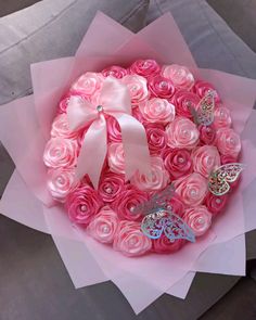 a bouquet made out of pink roses with butterflies on it and ribbons in the center