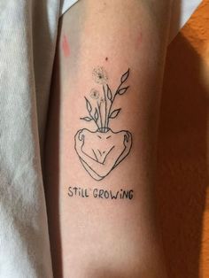 a tattoo on the arm that reads still growing with a plant in it's center