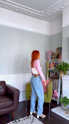 a woman is standing in the living room with her back to the camera and looking at something