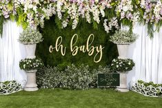 a baby shower backdrop with flowers and greenery