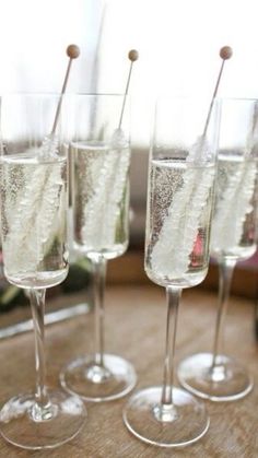 four wine glasses filled with champagne on top of a table