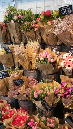 many different types of flowers are in buckets on the table and one is pink