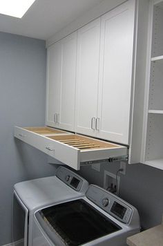 a washer and dryer in a small room with white cabinets on the wall