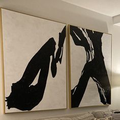 two black and white paintings hang on the wall above a couch in a living room