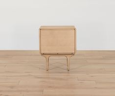 a small wooden table sitting on top of a hard wood floor next to a white wall