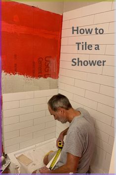 a man is painting the walls of a bathroom with red paint and white tiles on it