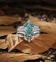 an image of a ring with turquoise stones and diamonds on it's sides sitting on leaves