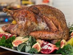 a roasted turkey on a platter with figs and other fruit