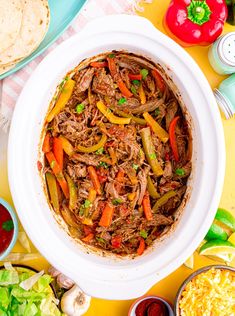 a large bowl filled with shredded meat and vegetables next to other foods on a table