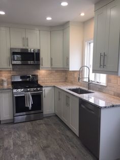 a kitchen with white cabinets and silver appliances