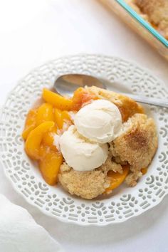 a white plate topped with fruit cobbler next to a bowl of icecream