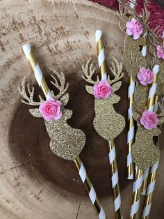 three gold and white paper straws with pink flowers on them are sitting in a bowl