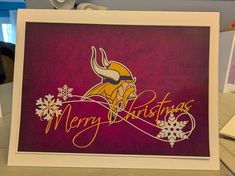 a greeting card with the word merry christmas written in gold and purple, featuring a viking's head