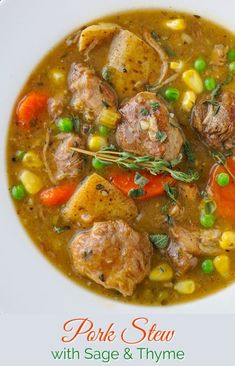 a white plate topped with meat and vegetables next to a bowl of soup on a table