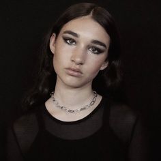 a woman wearing a black shirt and silver necklace with chains around her neck is looking at the camera