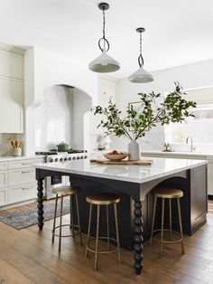 a kitchen island with three stools and a potted plant on it in the center