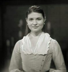 a black and white photo of a woman in an old - fashioned dress posing for the camera