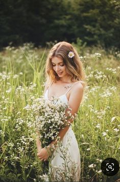 a woman in a white dress is standing in tall grass with flowers on her head